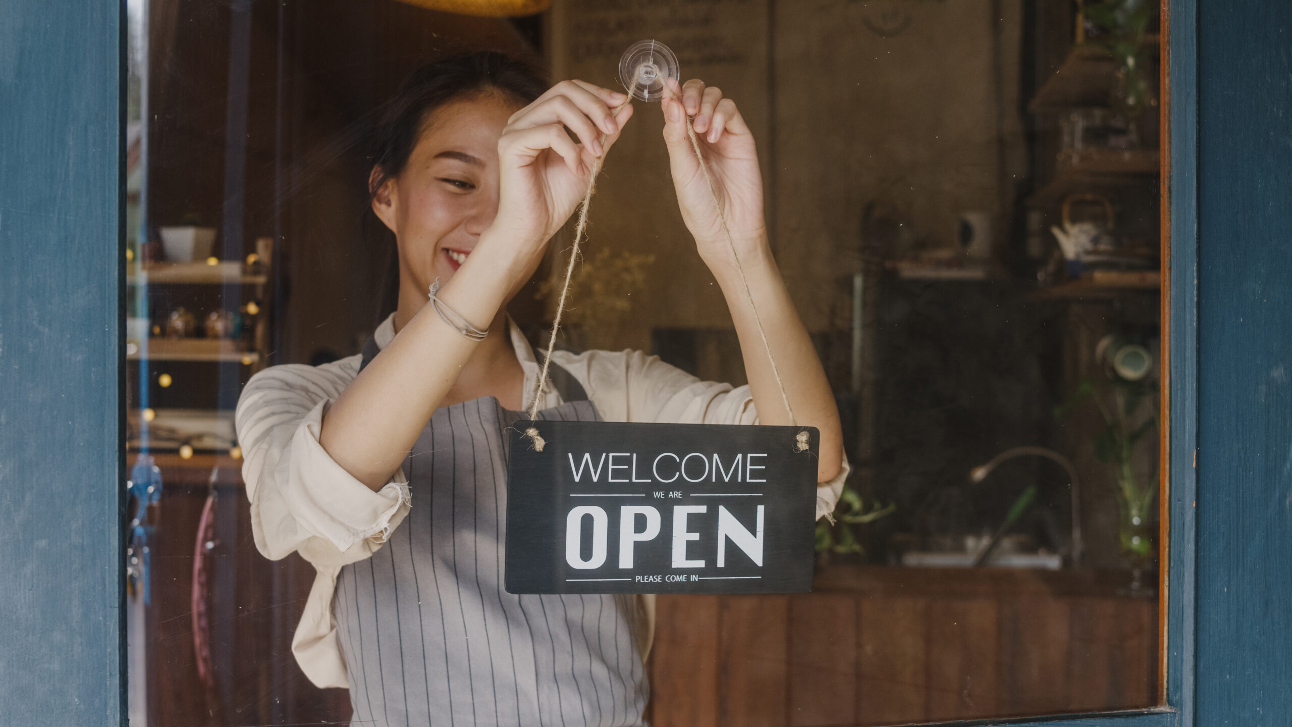 Woman shop owner hangs Open sign in her small business